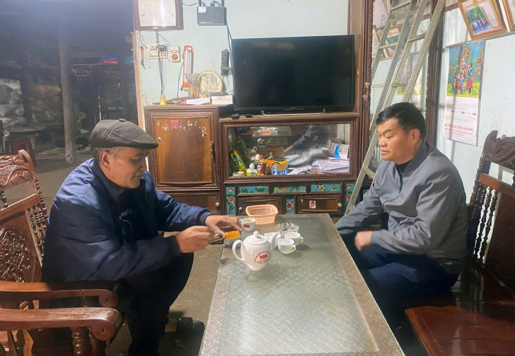 Ông Lục Xuân Hợi (bên trái), người có uy tín xóm Nặm Nhũng, xã Lũng Nặm trao đổi với cán bộ xã về tình hình xây dựng nông thôn mới tại xóm.